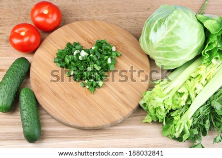 Heart shape of chopped herbs  and fresh vegetables, on wooden background