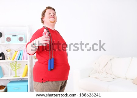 Large fitness man working out with skipping rope, at home