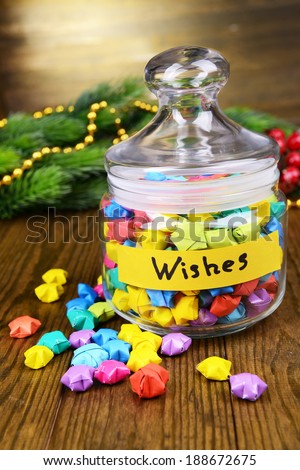 Paper stars with dreams in jar on table on wooden background