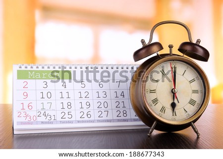 Alarm clock  and calendar on bright background