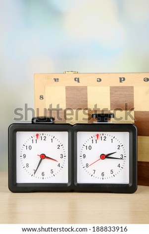 Chess clock and board on light background