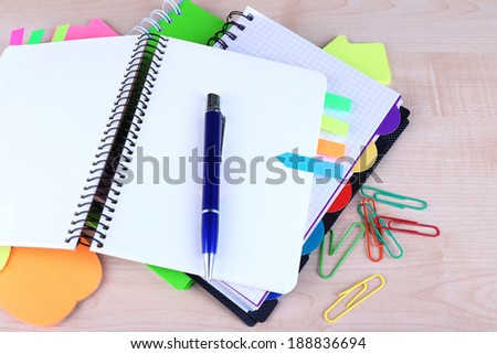 Notebook, pen, and stickers on wooden background