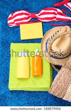Wicker bag, swimsuit, bottles with lotions on color background.