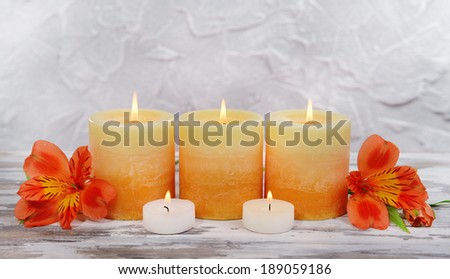 Beautiful candles with flowers on table on grey background