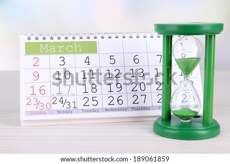 Hourglass and calendar on bright background