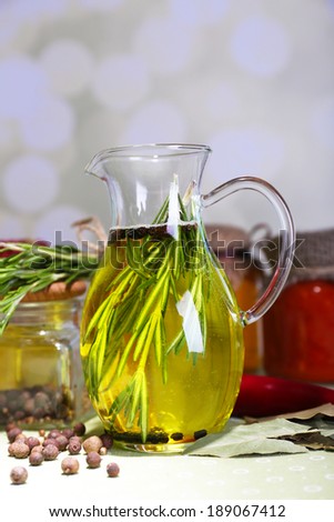 Essential Oil with rosemary in glass jug and jars with tasty sauces, on table, on gray background