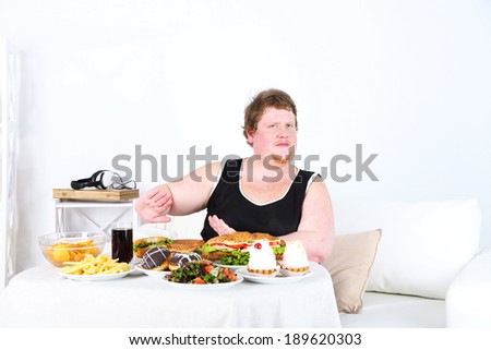 Fat man  do not want to eat a lot of unhealthy food, on home interior background
