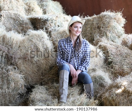 Beautiful cowgirl style model posing on farmland in hay