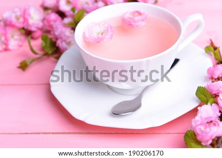 Beautiful fruit blossom with cup of tea on table close-up