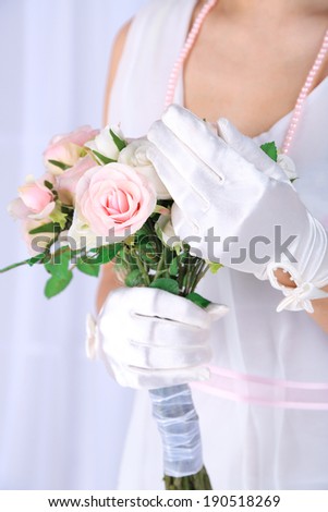 Beautiful bride in white gloves holding wedding bouquet, close-up