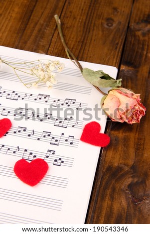 Red paper hearts on music book, close-up, on wooden background
