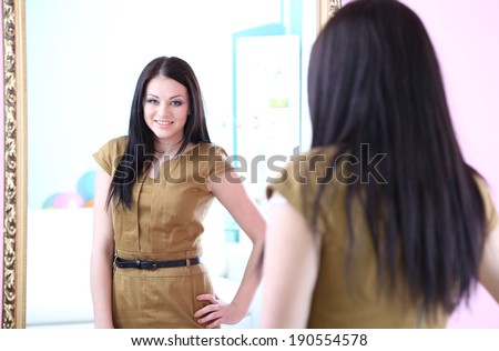 Young beautiful woman standing front of mirror in room
