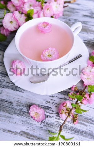 Beautiful fruit blossom with cup of tea on table close-up