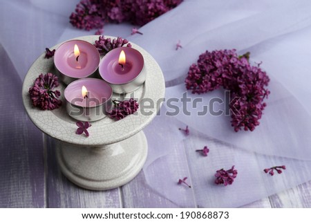 Beautiful candles and lilac flowers on wooden table