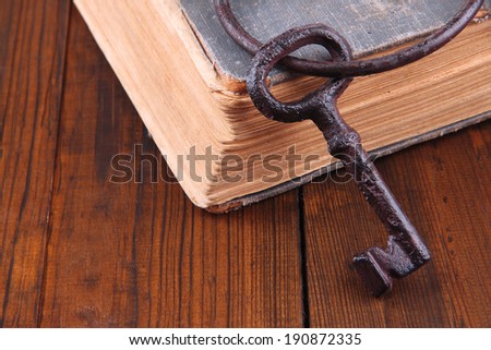 Old key with old book on wooden background
