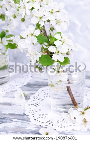 Beautiful fruit blossom in glass on table on grey background