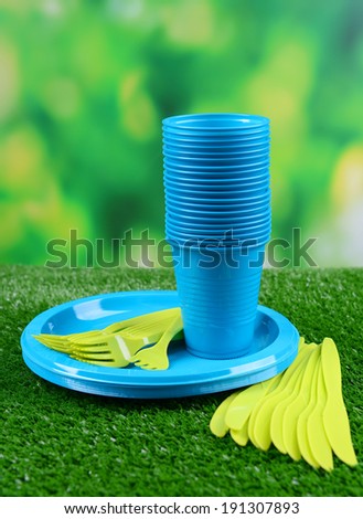 Bright plastic tableware on grass close-up