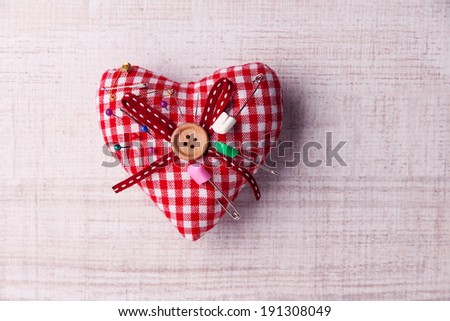 Fabric heart with color pins and safety pins on wooden background