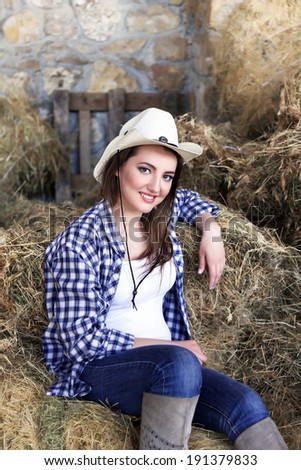 Beautiful cowgirl style model posing on farmland
