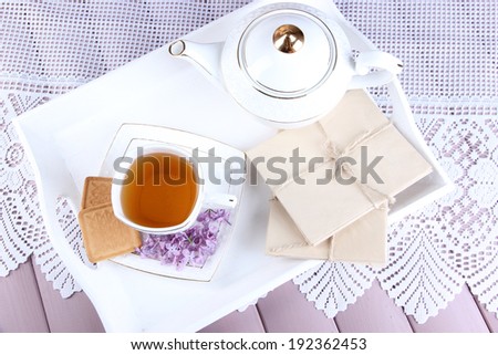 Composition with cup of tea, old letters on tray, on color wooden background