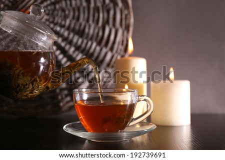 Tea pouring into glass cup on dark background