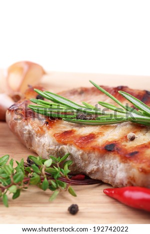 Grilled steak with spices, herbs and vegetables  on wooden board, isolated on white