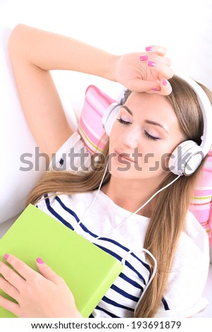 Conceptual image of  audio book. Beautiful girl with book and headphones.