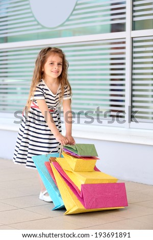 Happy little girl with shop bags, outdoors