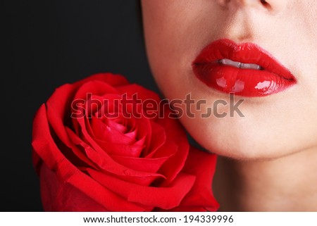 Girl with red lips and rose on dark background