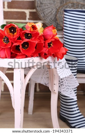 Bouquet of colorful tulips on chair, on home interior background