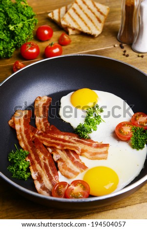 Scrambled eggs and bacon on frying pan on table close-up