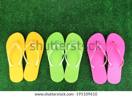 Bright flip-flops on green grass background
