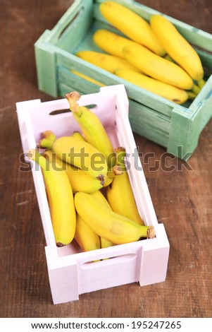 Bunch of mini bananas in wooden boxes on wooden background