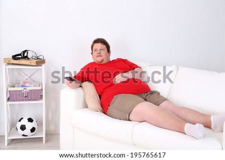 Lazy overweight male sitting on couch and watching television