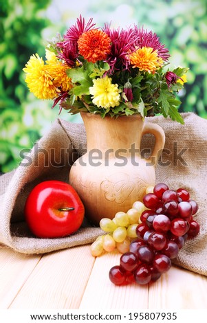 Composition with beautiful flowers in pitcher, and fruits,  on bright background