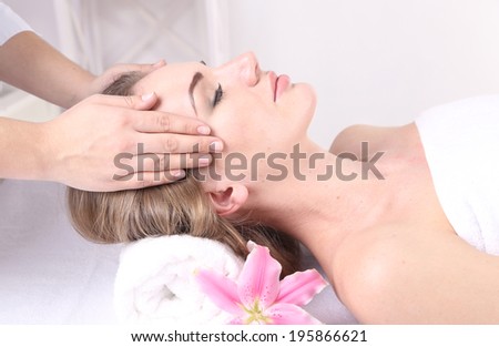 Beautiful young woman having head massage in spa salon