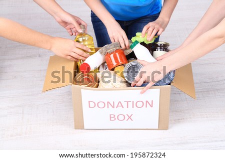 People makes foodstuffs out of donation box on grey background
