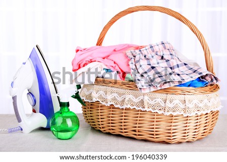 Colorful clothes in basket on table, on light background
