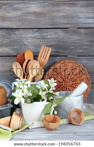 Composition of wooden cutlery, mortar, bowl and cutting board on wooden background