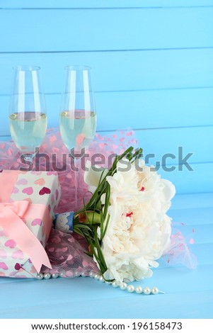Beautiful wedding bouquet, gift box and wine glasses on  color background