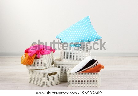 Plastic baskets with things in floor on room background