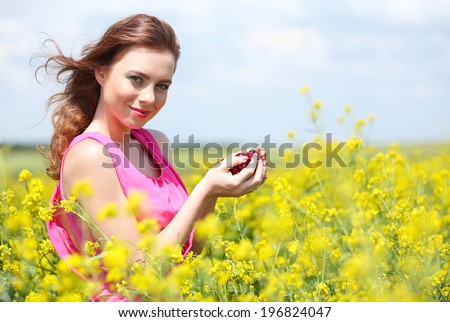Beautiful young woman with cherries in field