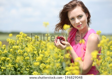 Beautiful young woman with cherries in field