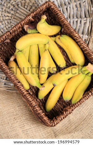 Bunch of mini bananas in wicker box on sackcloth background