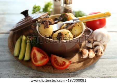 Young boiled potatoes in pan with vegetables on table in kitchen
