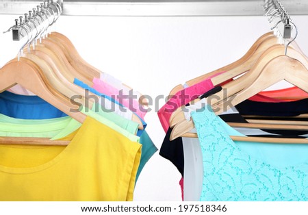 Different clothes on hangers on light background