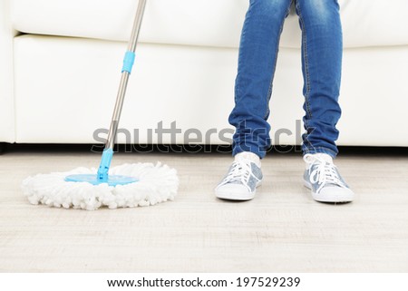 Woman resting on sofa after cleaning wooden floor from dust