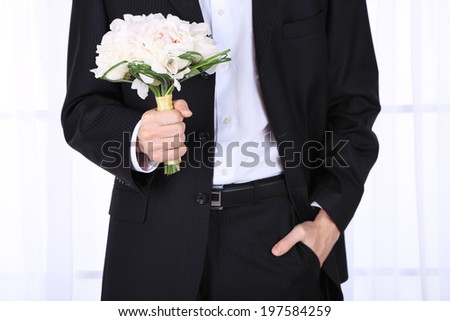 Man holding wedding bouquet on light background