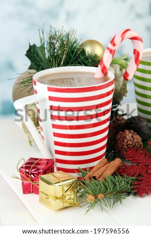 Cup of hot cacao with chocolates and Christmas decorations on table on bright background