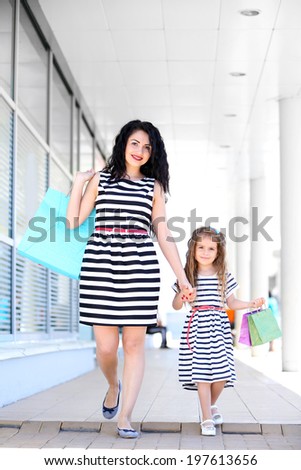 Happy mom and daughter with shop bags, outdoors